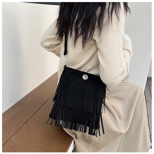 Detail of black suede crossbody bag with layered fringe and round metal magnetic buckle