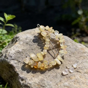 Detail of crescent moon hair clip with natural yellow crystals on a grey rock surface