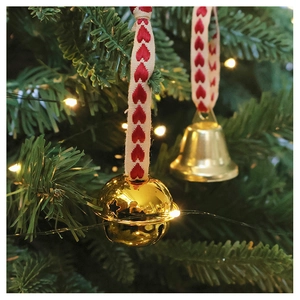 Close-up of star cutout bells with red heart ribbons hanging on a Christmas tree branch