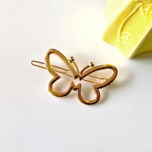 Gros plan sur une pince à cheveux papillon évidée en métal doré au fini poli brillant