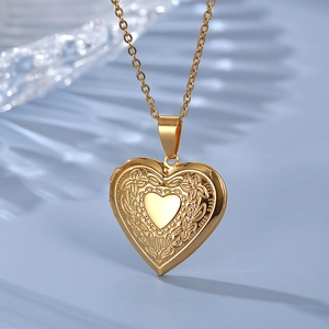 Golden heart locket necklace with vintage floral engraving on light blue background