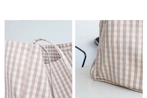 Detail view of reinforced stitching and woven texture on beige striped canvas tote bag