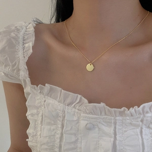 Close-up of minimalist gold circular pendant necklace worn on neck for a dainty elegant look
