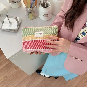 Detail of hand-held colorful striped woven toiletry bag with vibrant texture and label