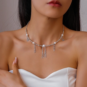 Detail of silver pearl necklace with layered fringe tassels on a model's collarbone