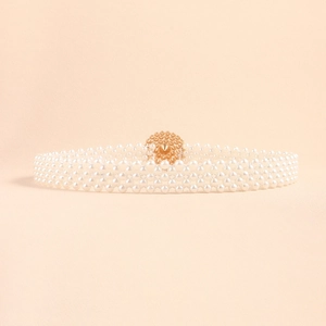 Detailed close-up of multi-layer white pearl waist chain with textured gold buckle