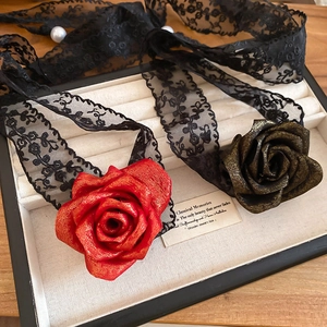 Detail of red rose pendant with gold dust finish and black lace ribbon and pearl