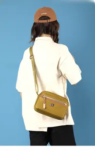 Detail showing the mustard yellow nylon shoulder bag with zipper pockets and adjustable strap