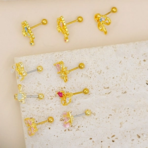 Collection of gold stud earrings with colorful crystals on a marble stone surface