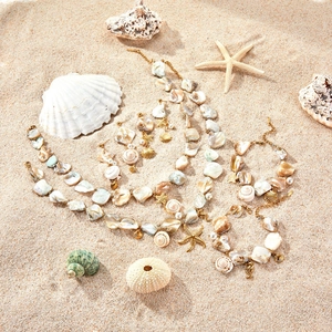 Ocean theme jewelry set with gold starfish and shells on a sandy beach setting