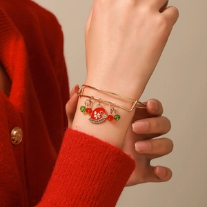 Close-up of golden Christmas charm bracelet with snowflake and reindeer on model's wrist