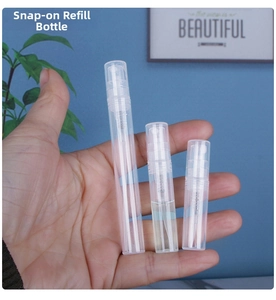 Three sizes of clear plastic perfume spray bottles held in hand for detail view