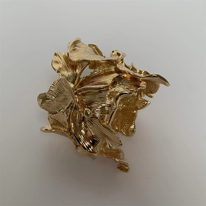 Detail shot showing the intricate layered metal leaf texture and golden finish on the cuff