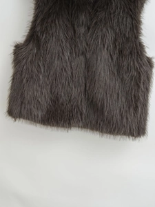 Detailed texture of thick dark grey faux fur vest showing plush shaggy synthetic hair