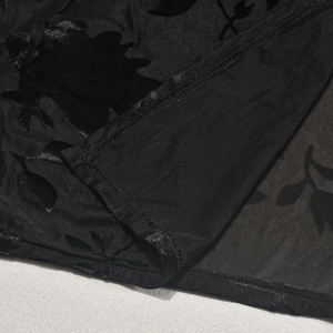 Close-up of black sheer mesh fabric featuring textured floral flocking details