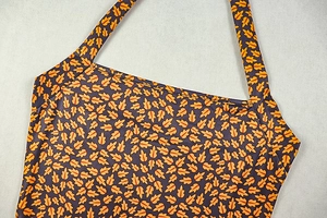 Detail of deep purple halter dress with orange maple leaf print and clean edge stitching
