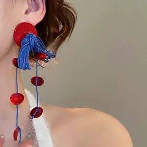 Bohemian silver needle drop earrings featuring red discs and blue wax cord tassels
