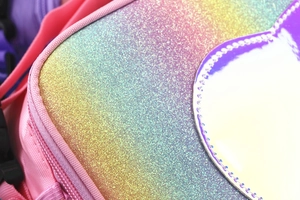 Macro detail of glitter rainbow lunch bag featuring a holographic purple heart patch