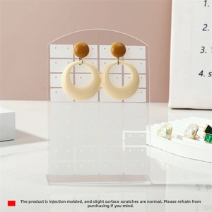Detail of ochre and beige round stud earrings displayed on a clear acrylic stand