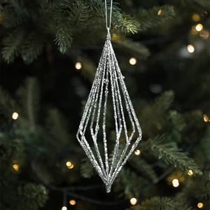 Silver star Christmas ornament with glitter finish hanging on a lit Xmas tree