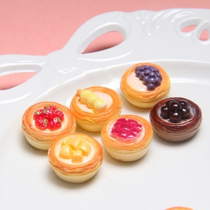 Close-up of six miniature resin fruit tart models with strawberry and mango details