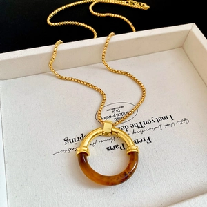 Dettaglio macro della collana con ciondolo tondo in resina retrò e catena dorata lucida