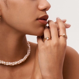 Close-up of elegant 18k gold plated stainless steel pearl rings and necklace on model