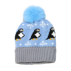 Winter blue knitted hat for kids with penguin pattern and fluffy blue pom pom on top