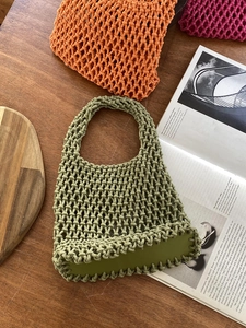 Detail of green woven cotton rope tote bag showing the durable PU base on wooden table