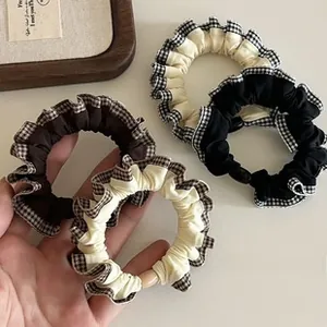 Close-up of four gingham-edged elastic hair scrunchies in coffee, cream, and black tones