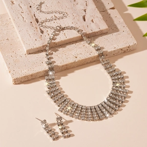 Macro detail of luxury rhinestone fringe necklace and earring set on textured stone
