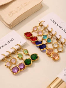 Macro view of gold stainless steel earrings with colorful square Czech glass pendants