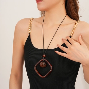 Detail of a brown square resin pendant with a round bead on a long cord necklace