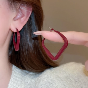 Close-up of minimalist geometric rhombus earrings in deep wine red on model