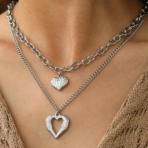 Detail of layered silver necklace with hammered heart and hollow wing pendants