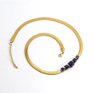 Close-up of golden herringbone necklace featuring five blue rectangular cut gemstones