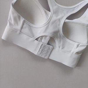 Detail view of white sports bra racerback with 3-row hook-and-eye closure and mesh