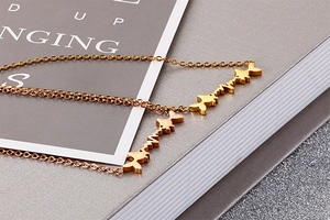 Close-up of golden stainless steel necklace with interlocking fish pendants on a desk