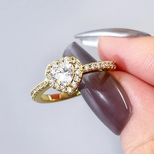 Macro shot of a gold heart-shaped halo ring with sparkling zircon stones on a female hand