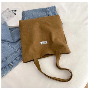 Detailed view of a brown corduroy tote bag with Fashion Insence label on white bedding