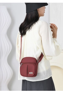 Detailed view of a practical burgundy nylon crossbody bag with multiple zipper pockets