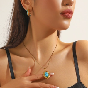 Close-up of model wearing gold-plated vintage heart necklace and turquoise earrings set