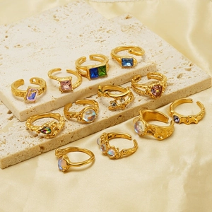 Detailed view of vintage gold-plated rings with colorful stones on white travertine base