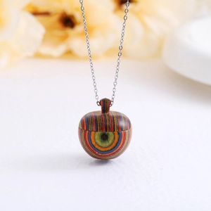 Macro shot of striped wooden pinecone pendant on a slim silver chain with floral background