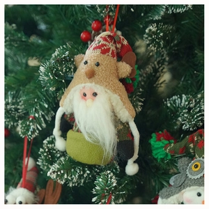 Detail of a gnome plush ornament hanging on a Christmas tree branch with red berries