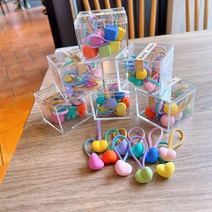 Close-up of heart-shaped colorful hair tie sets in clear gift boxes on wooden surface