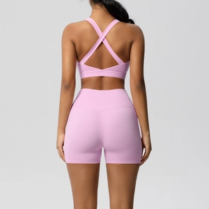 Rear view of pink high-waisted yoga shorts and cross-back sports bra set on model