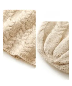 Close-up of beige cashmere knit beanie showing detailed cable stitch texture and soft fabric