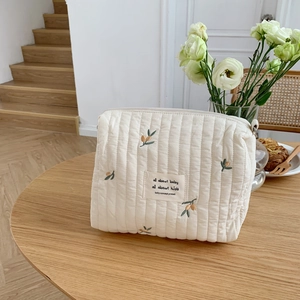 Close-up of quilted baby stroller bag with olive embroidery and a zipper closure