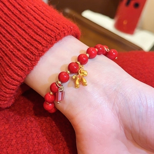 Nahaufnahme eines roten Achat-Perlenarmbands mit einem goldfarbenen Pferdeschmuck am Handgelenk